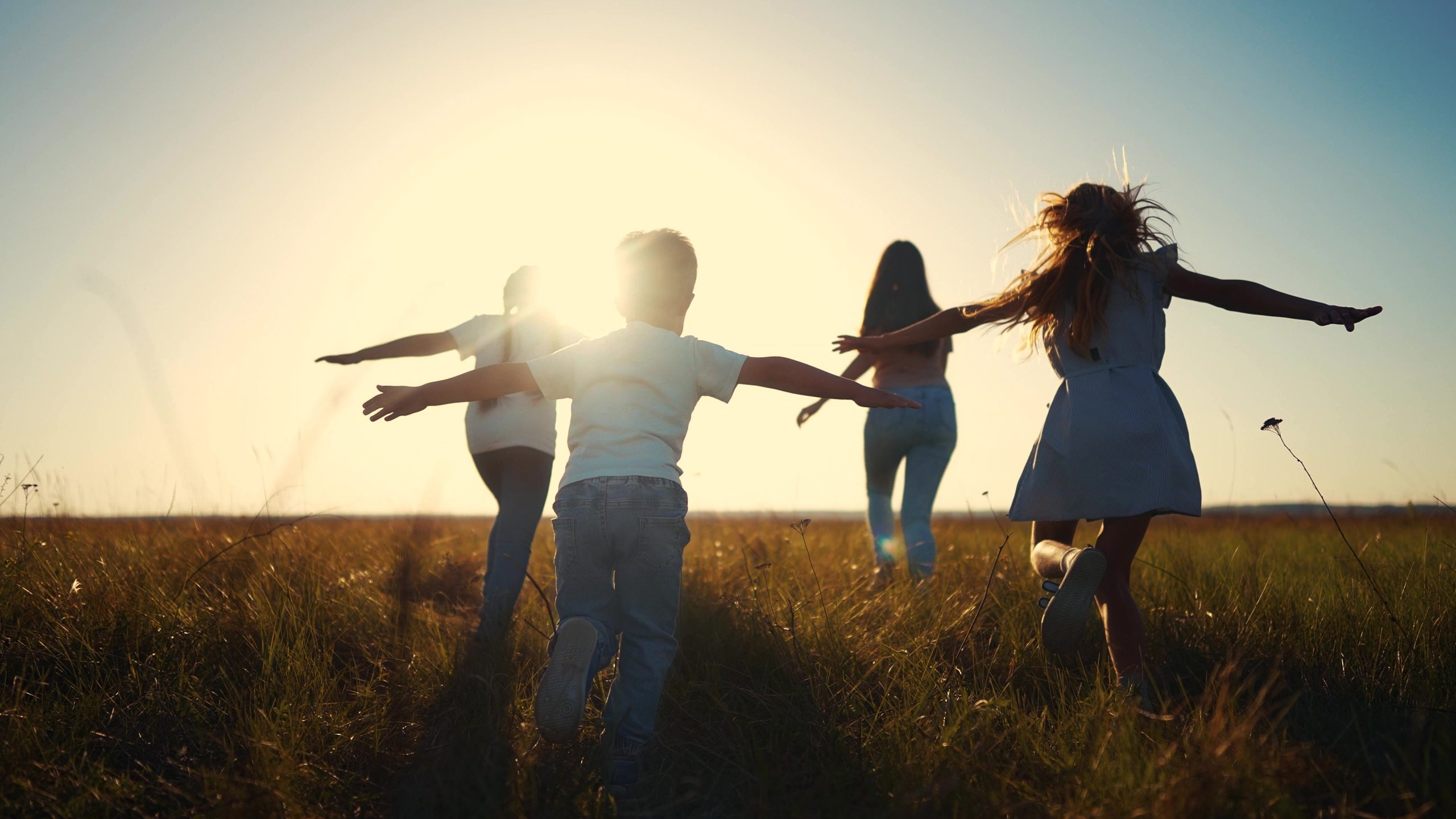 Children running and playing in a sunlit field.