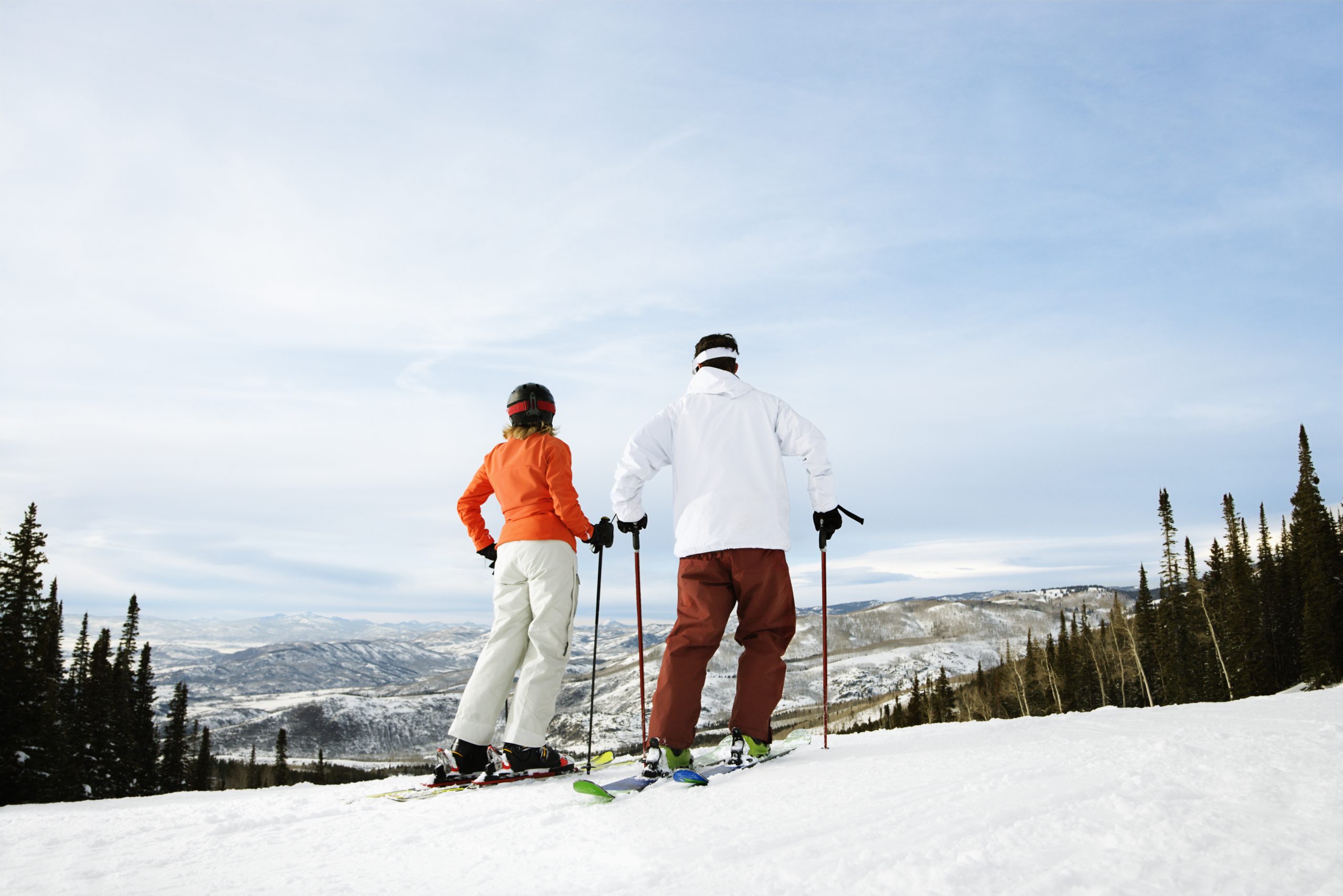 A couple on skis at the top of a snowy hill in one of the best US cities for winter sports.